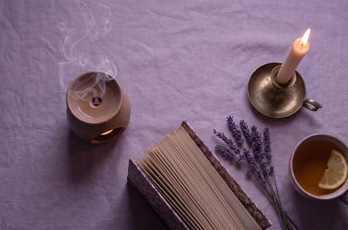 Peaceful slow living flatlay with lavender candle herbal tea and open book on linen