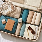 Aesthetic carry-on suitcase flatlay with travel essentials passport and journal on white bed