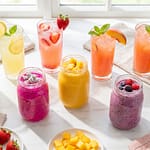 Colorful homemade lemonade and smoothie drinks in glasses and mason jars with fresh fruit garnishes