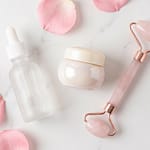 Clean beauty skincare flatlay with glass bottles and rose petals on marble